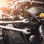 Mechanic hand checking and fixing a broken car in car service garage